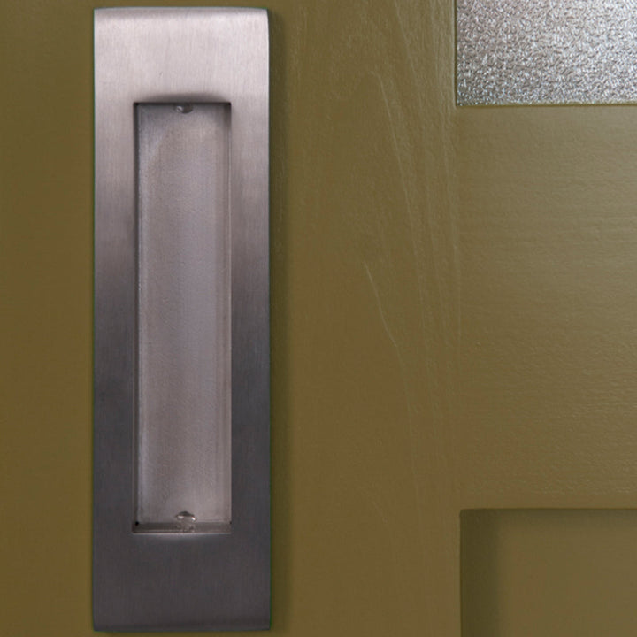 A close up of a 1925Workbench Flush Door Pull on a door.