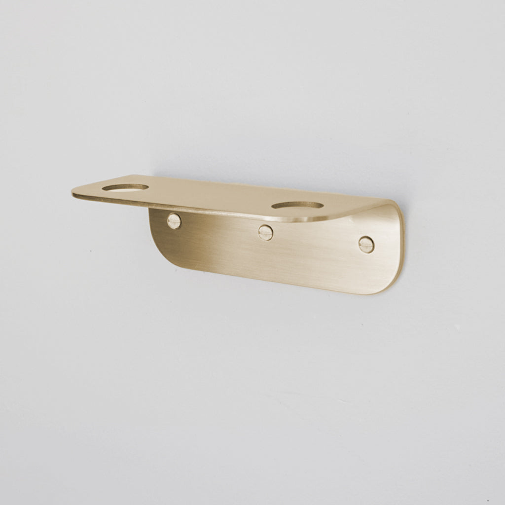 Bende Double Soap Holder in Satin Brass mounted on white wall with 3 slot head screws