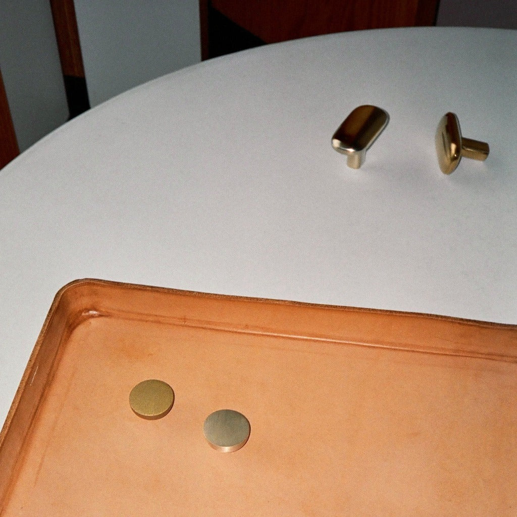Brass Maha Alavi Cercle half knobs on a white table.