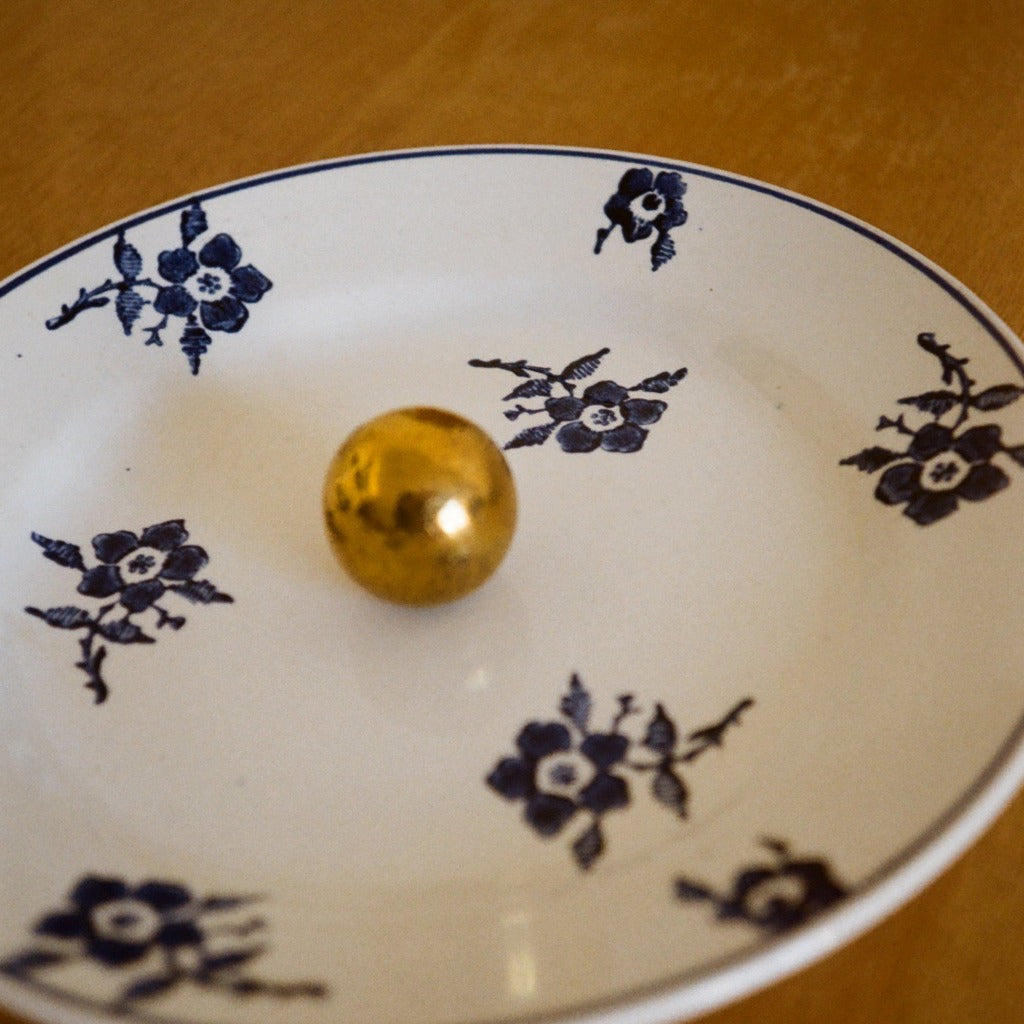 Brass Maha Alavi Cercle medium knob on a blue floral plate.