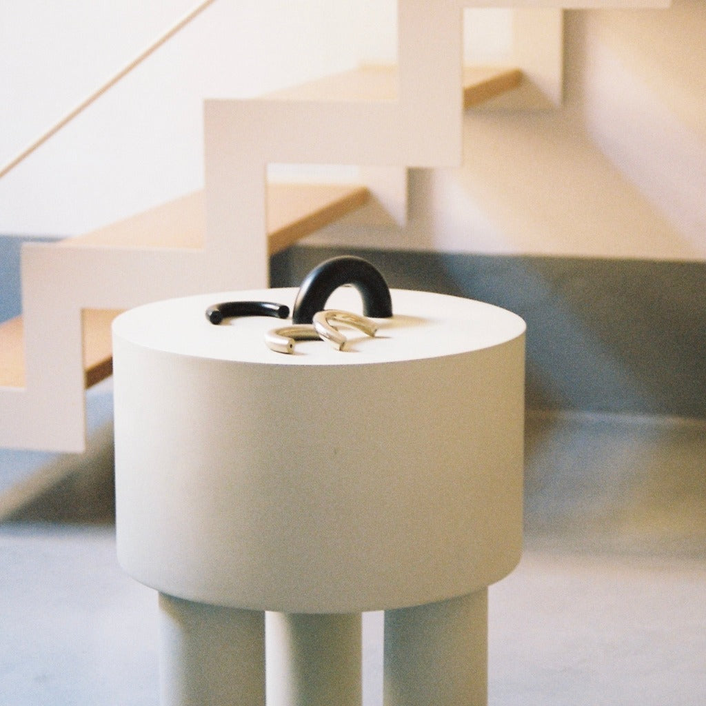 Matte black Maha Alavi Cercle thin pull on a white cylinder table.