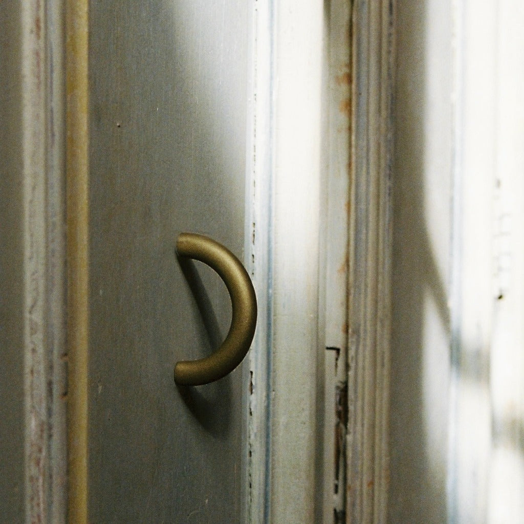 Brass Maha Alavi Cercle thin pull on a weathered door.