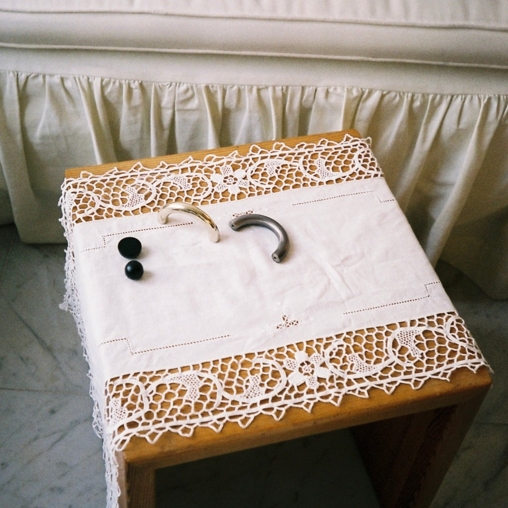 Cream and pewter Maha Alavi Cercle thin pulls on a lace-covered table.