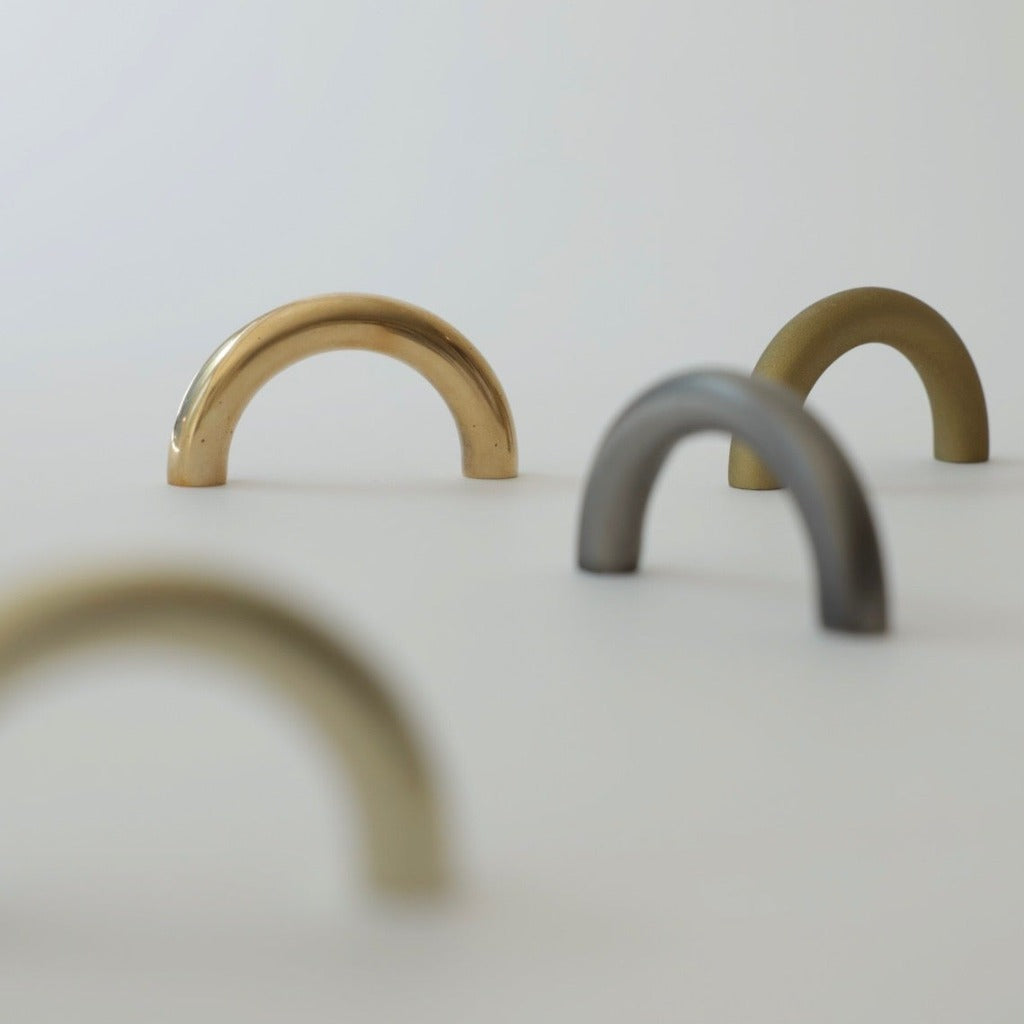Brass and nickel Maha Alavi Cercle thin pulls grouped on cream.