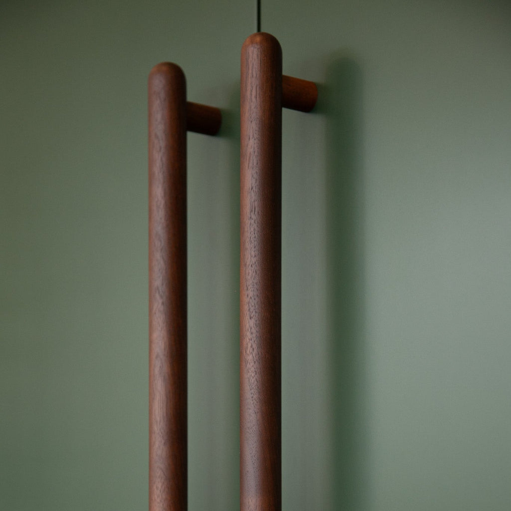 Walnut Chapman & Bose wood bar pulls on a green wall.