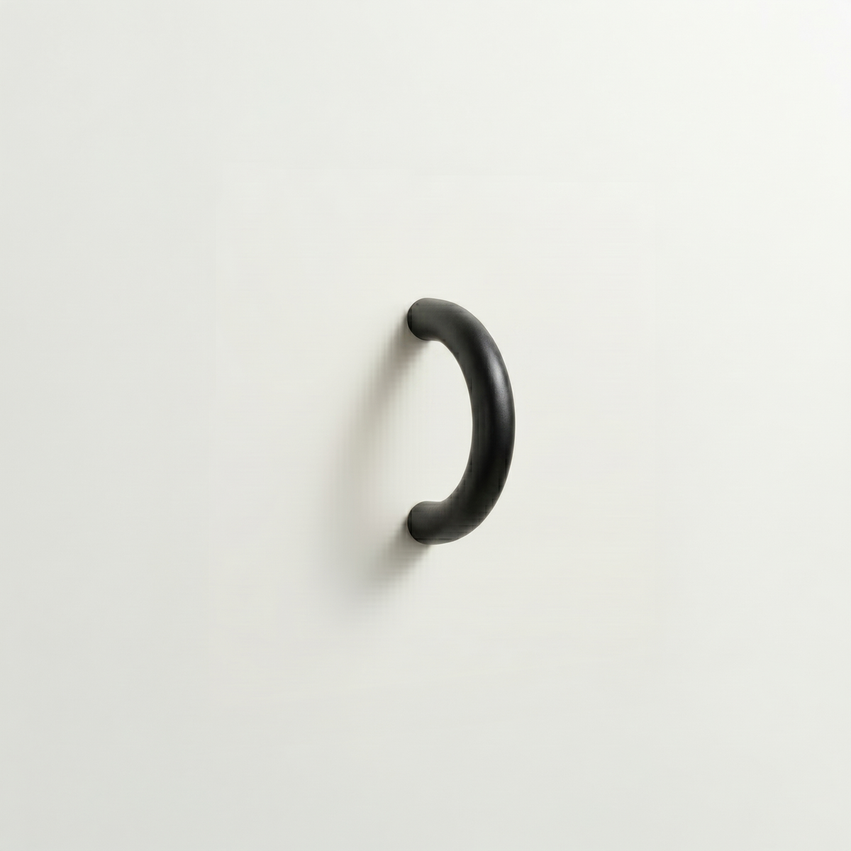 Matte black Charlie Arc pull, a small half-round arc handle, mounted on a white surface.