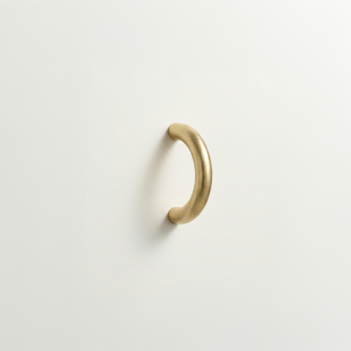 Satin brass Charlie Arc pull, a small half-round arc handle, mounted on a white surface.