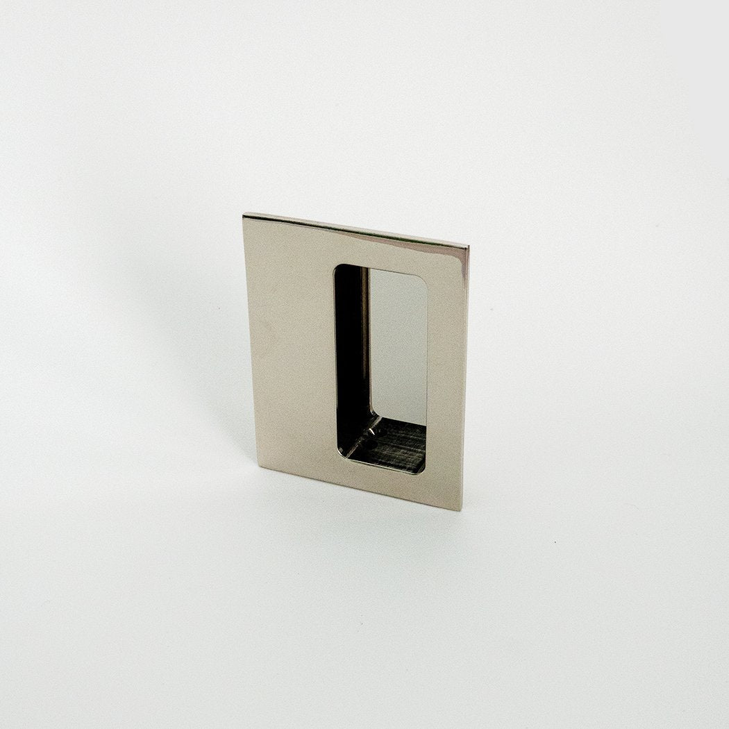 Polished nickel Charlie 333 flush drawer and door pull, a rectangular recessed pull with a deep finger pocket, installed in a white door.