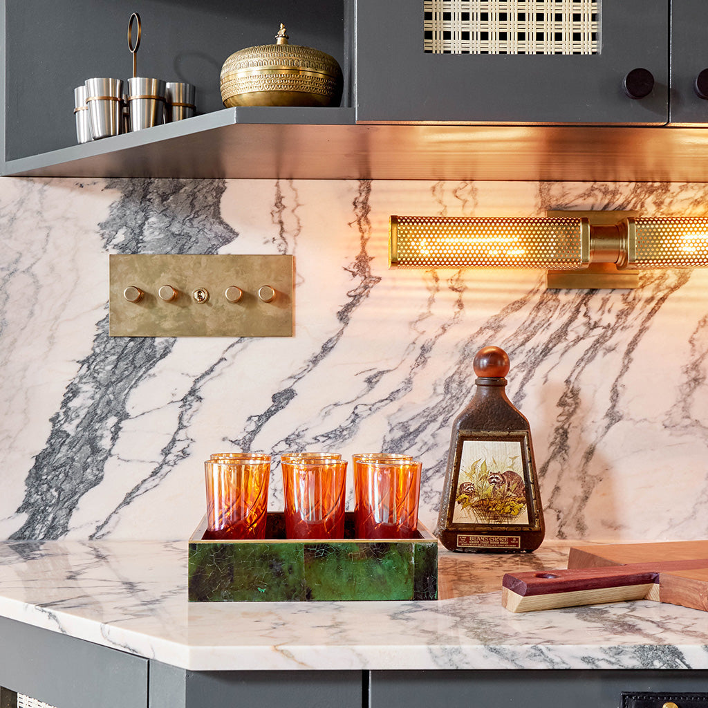 A kitchen with a marble backsplash and brass Forbes & Lomax switches.