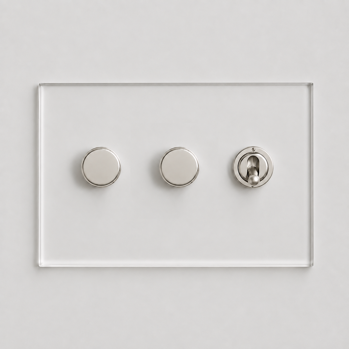 Forbes & Lomax Invisible clear acrylic plate with two nickel rotary dimmers and one nickel toggle switch on a white wall.