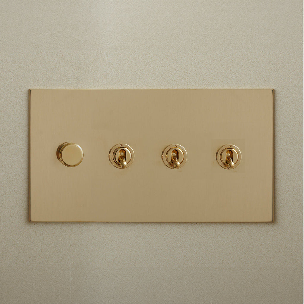 Brass Forbes & Lomax switch plate with a dimmer and three toggles.