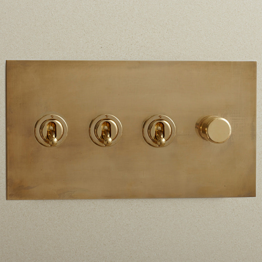 Aged brass Forbes & Lomax switch plate with three toggles and a dimmer.