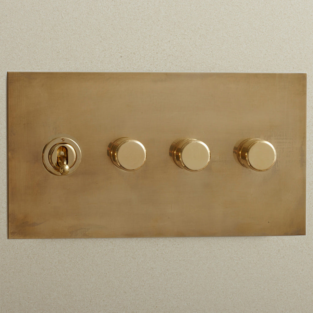 Aged brass Forbes & Lomax switch plate with a toggle and three dimmers.