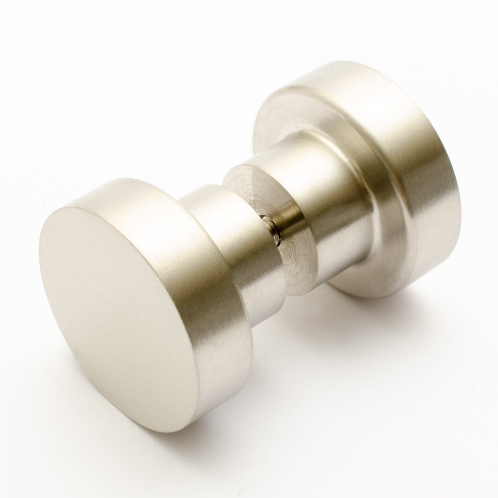A close up of two Baccman Berglund Dot Shower Door Knobs on a white surface.