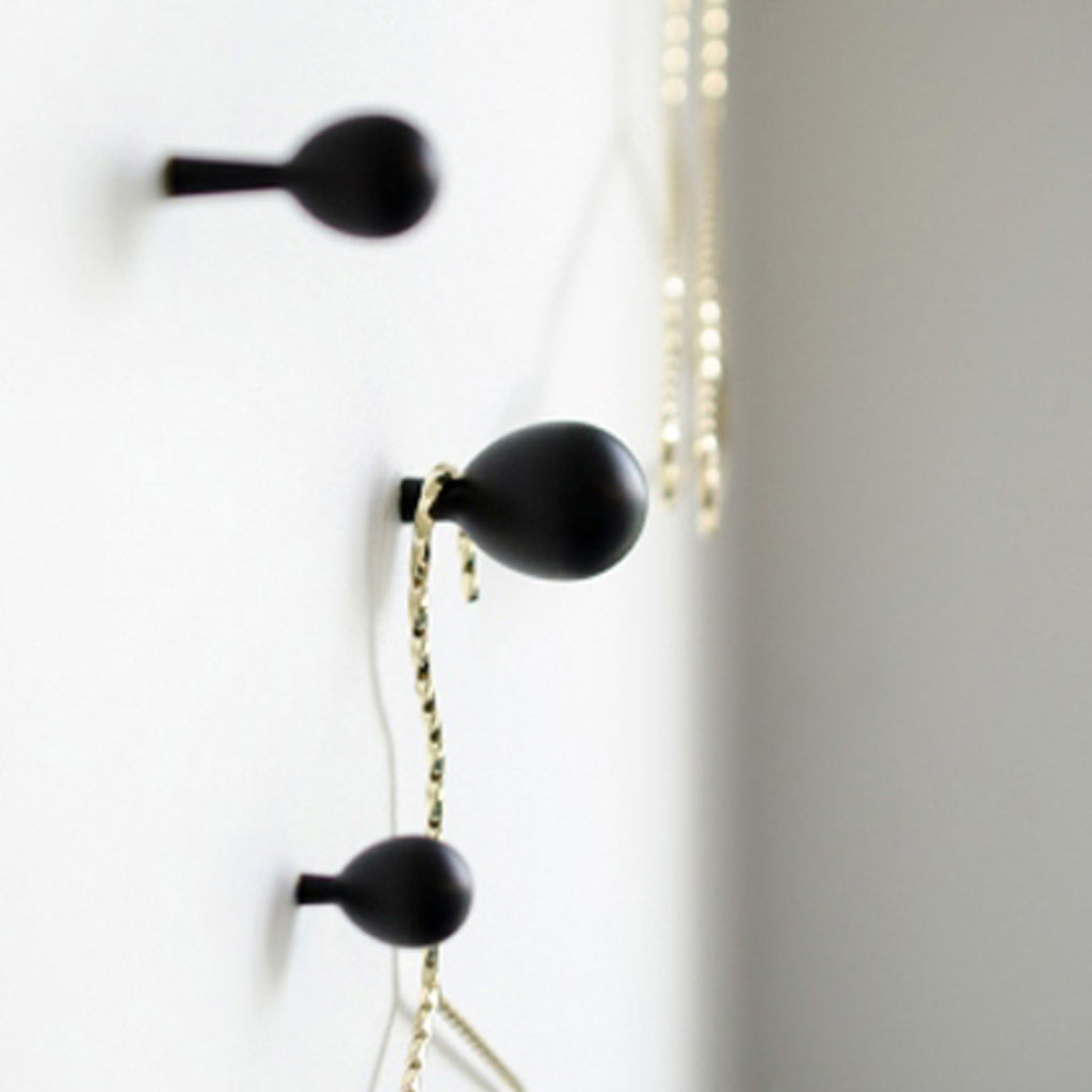 A white wall with some black Baccman Berglund Drop Knobs/Hooks 28 on it.