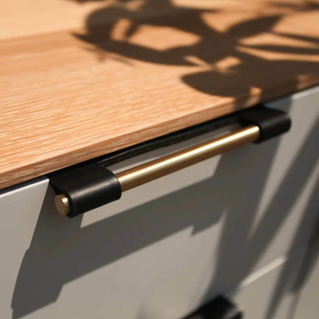 Chapman & Bose EP03 leather edge pull with an exposed satin brass core on a wood drawer.