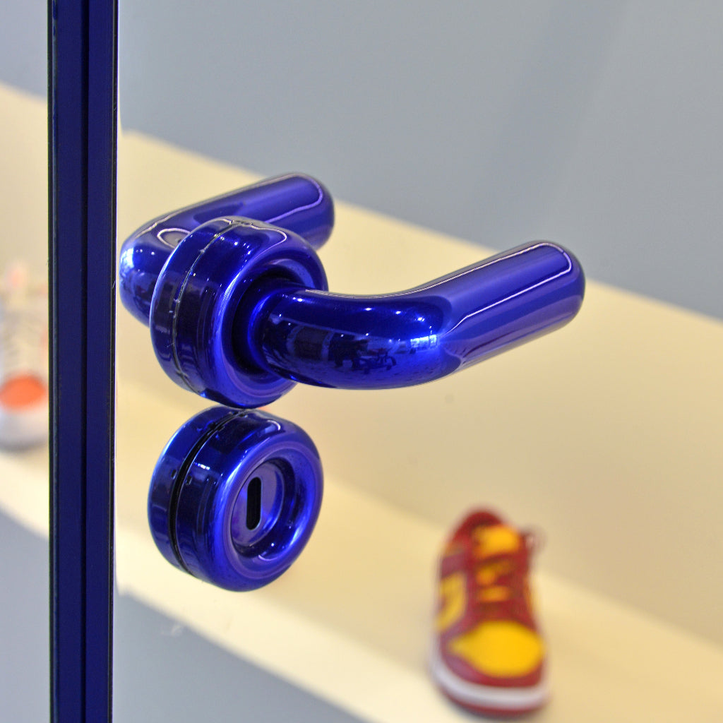 Blue glass d line FAT door lever on a door in a playful styled scene.