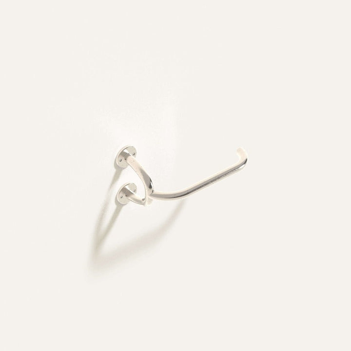 Fauna Toilet Roll Holder in polished stainless steel installed on a white wall