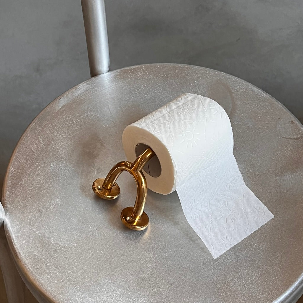 Brass Maha Alavi Fauna toilet paper holder on a metal table.