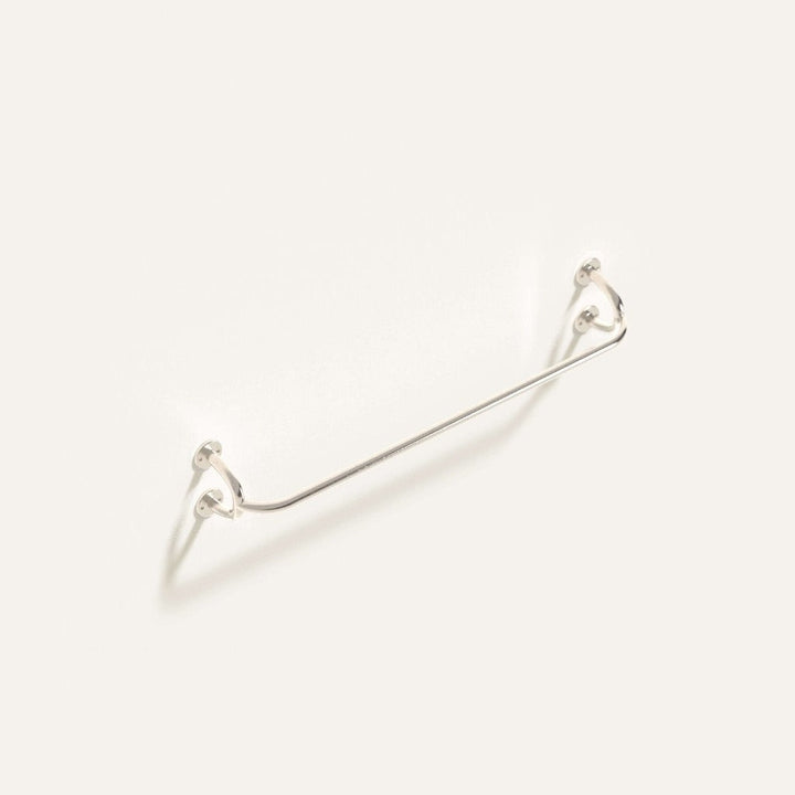 Fauna Towel Bar in polished stainless steel installed on a white wall showcasing it's gentle curves and clean lines.