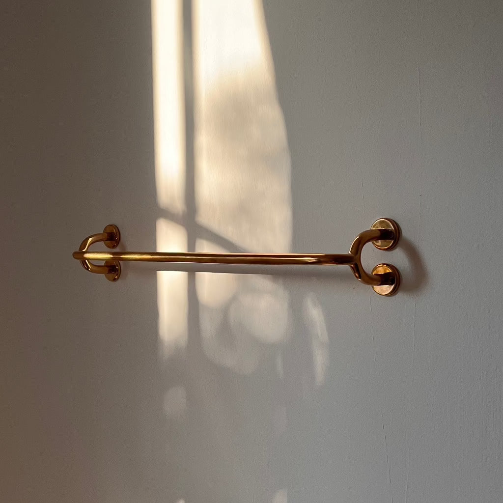 Brass Maha Alavi Fauna towel bar on a white wall.