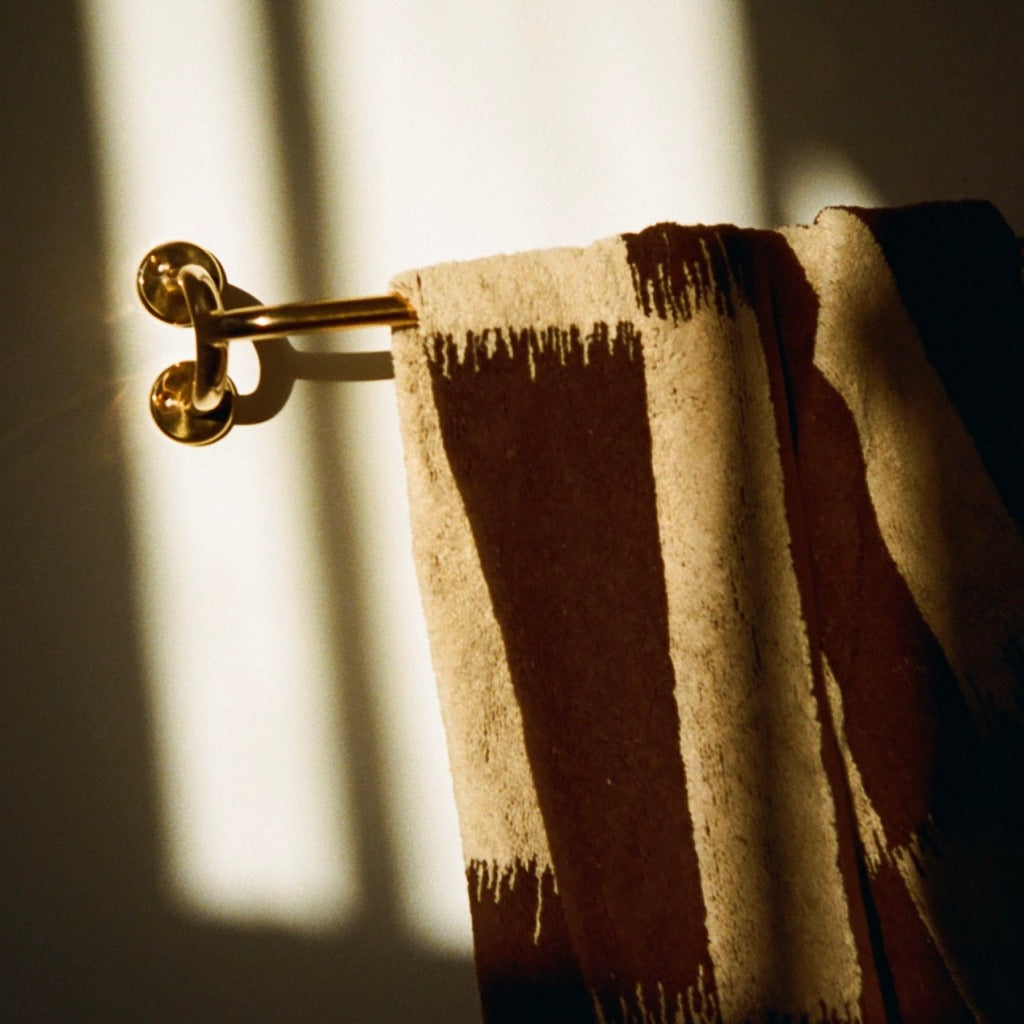 Brass Maha Alavi Fauna towel bar with a brown towel.
