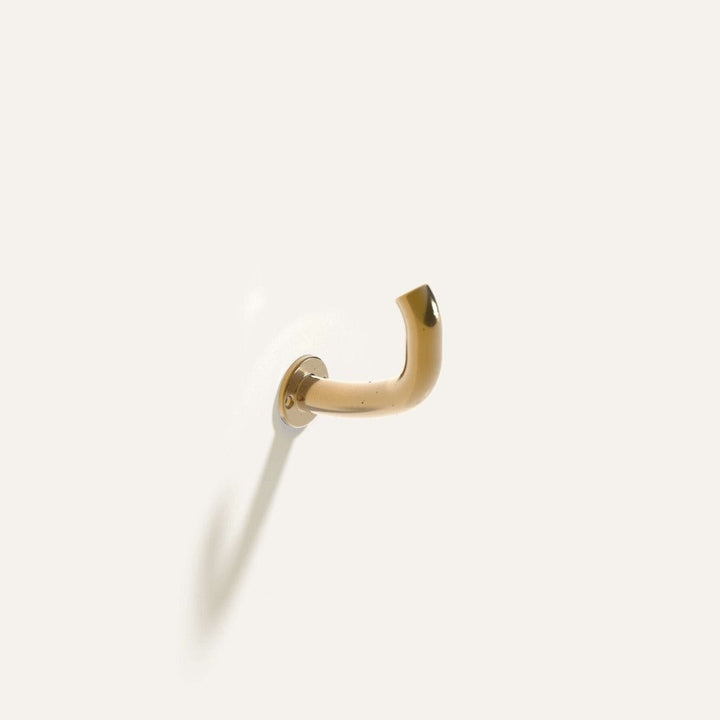 Fauna Wall Hook in polished brass installed on a white wall.