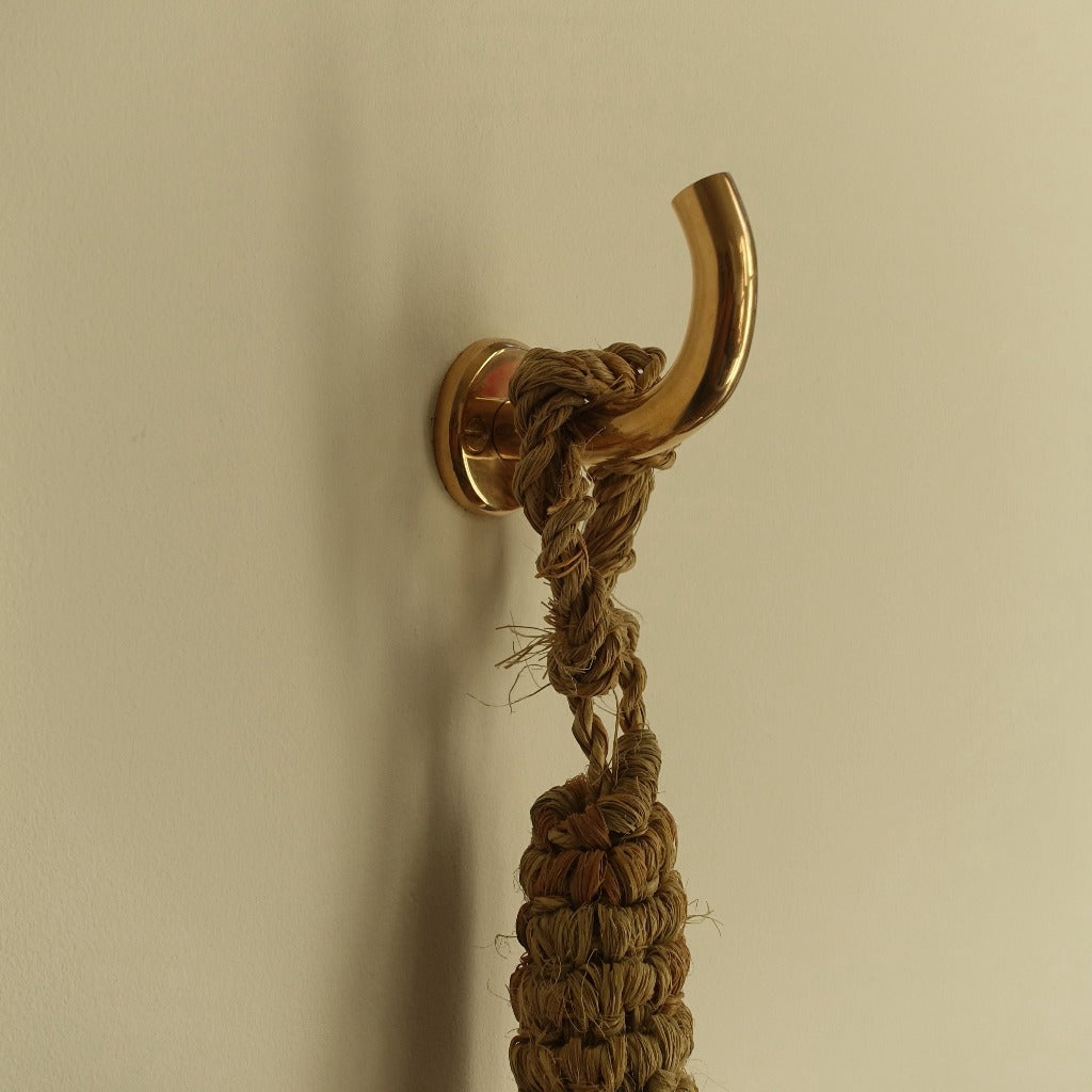 Brass Maha Alavi Fauna wall hook holding a braided rope.