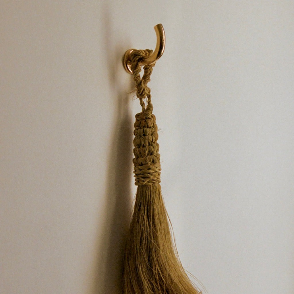 Brass Maha Alavi Fauna wall hook holding a tassel.
