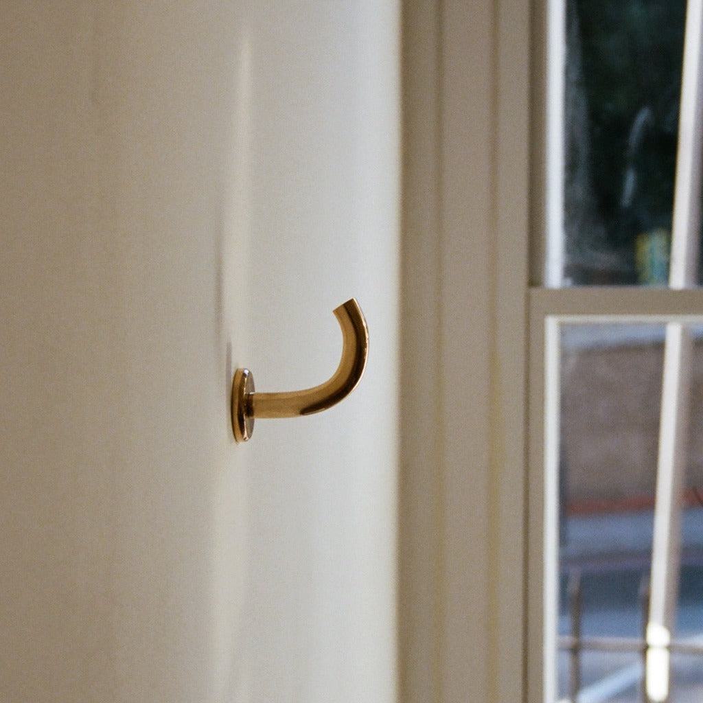 Brass Maha Alavi Fauna wall hook by a window.