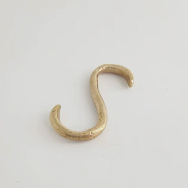 A Mi & Gei Forme No. 1 Hanging Rail hook in gold color on a white surface.