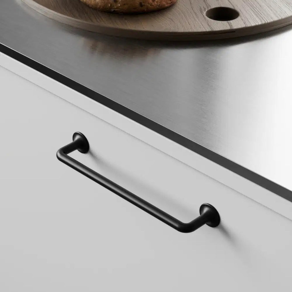 Black cabinet pull mounted on white drawer