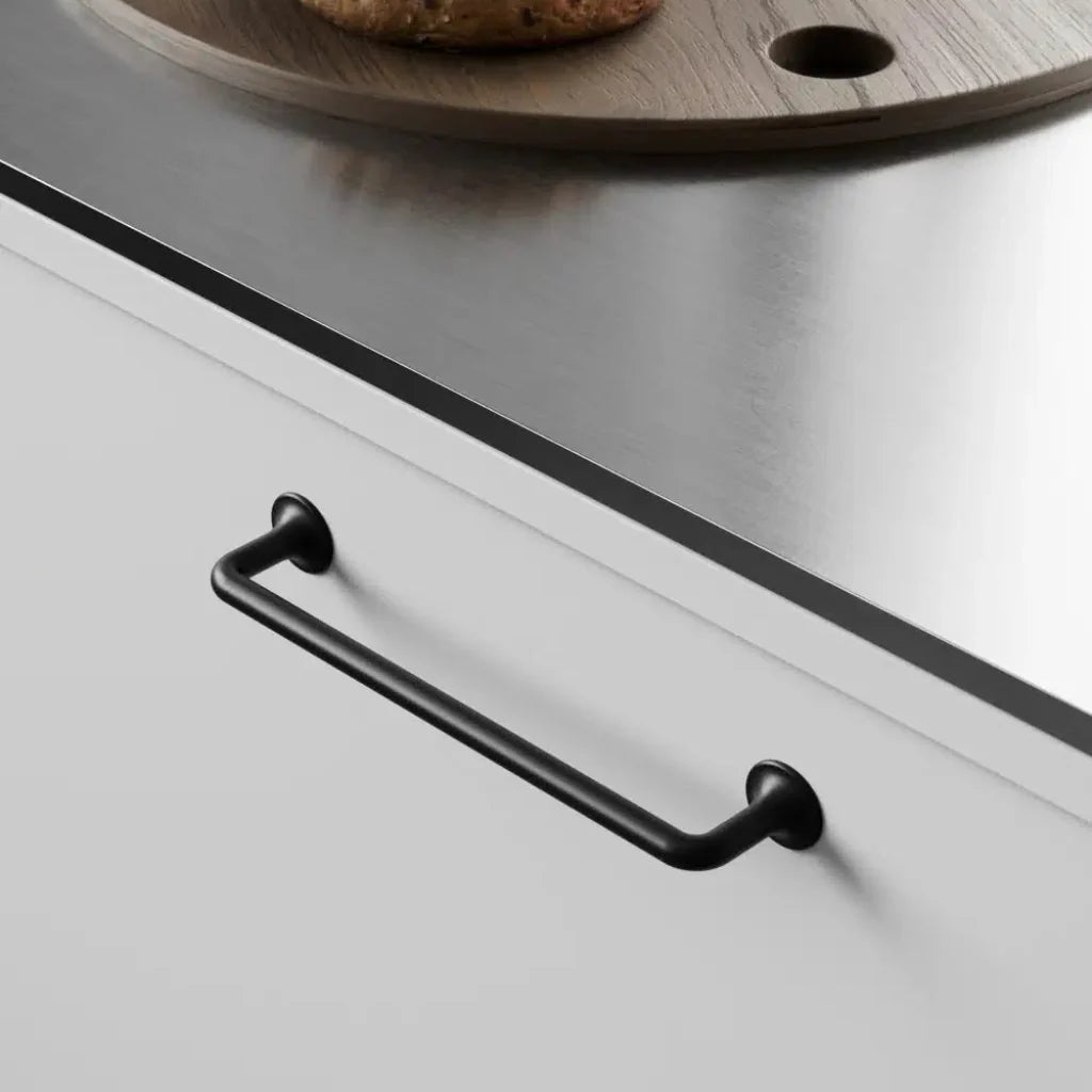 Black cabinet pull mounted on white drawer