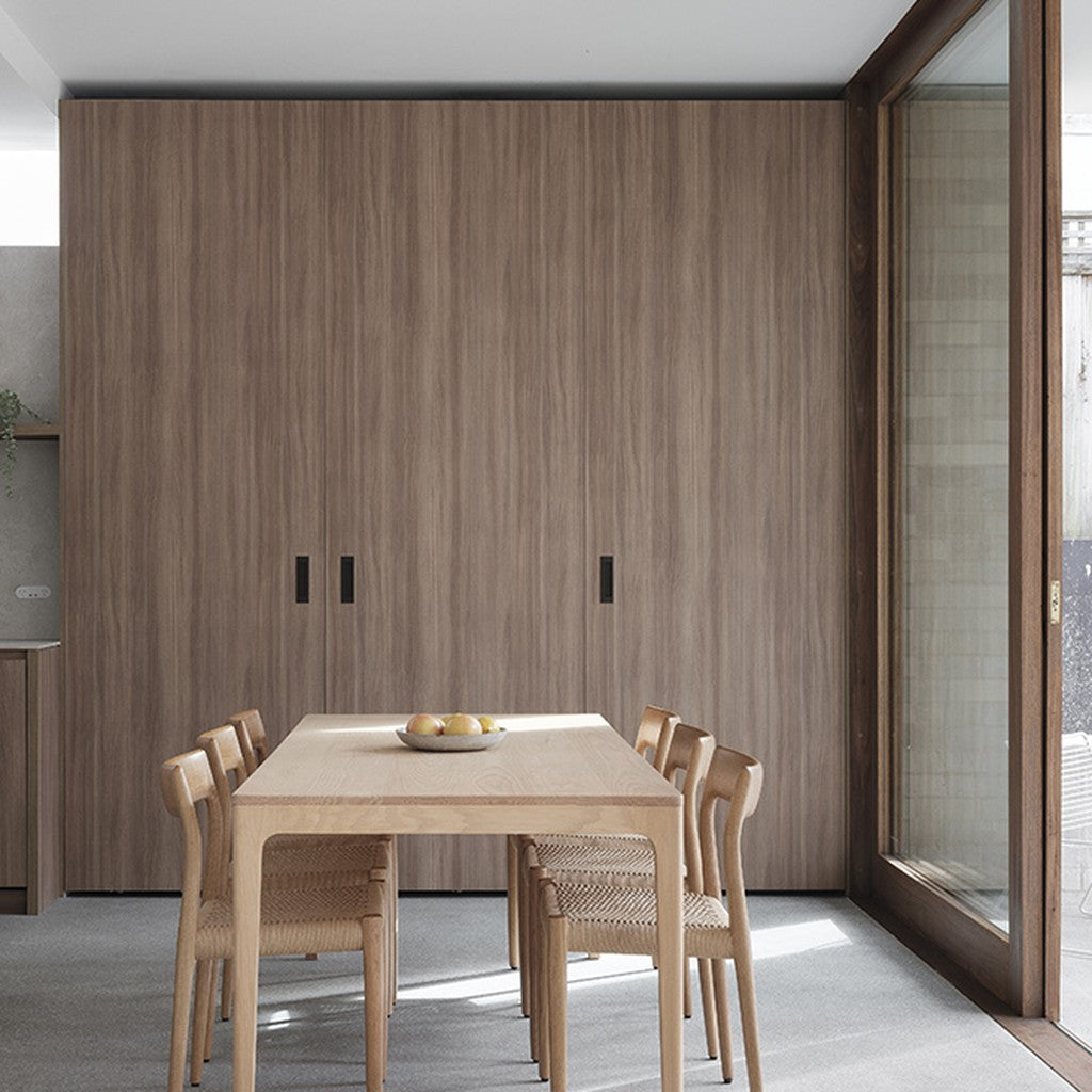 HB 675 bi-fold flush pulls in black, recessed into full-height walnut cabinetry in a dining room.