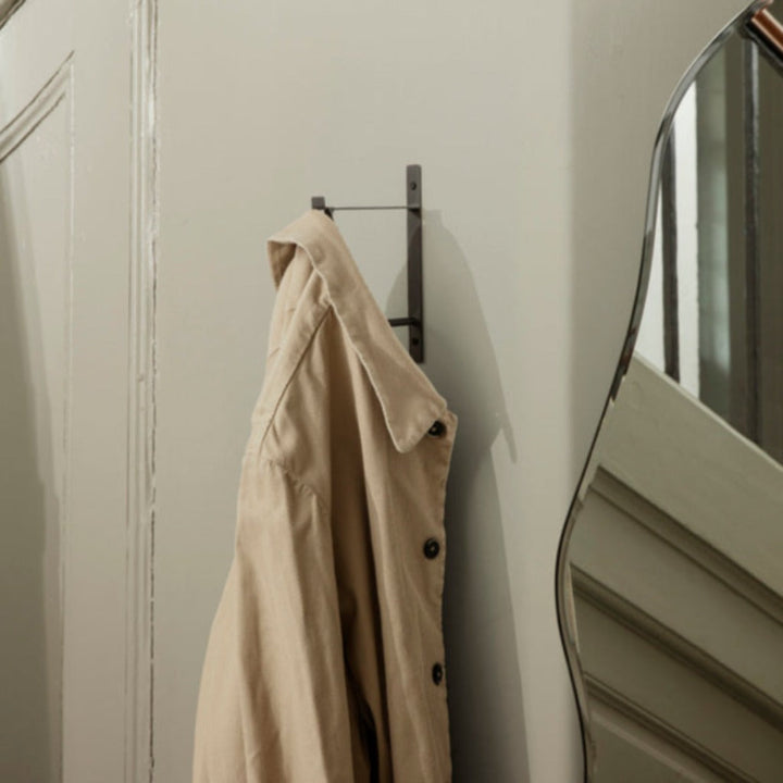 hang rack in black brass on wall holding beige jacket