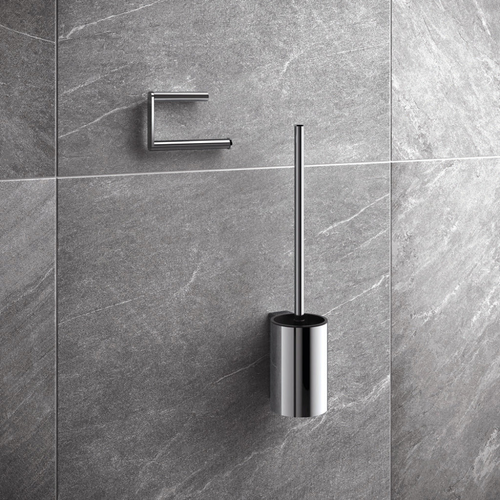Polished chrome Hewi 900 toilet roll holder and brush unit on a grey stone wall.