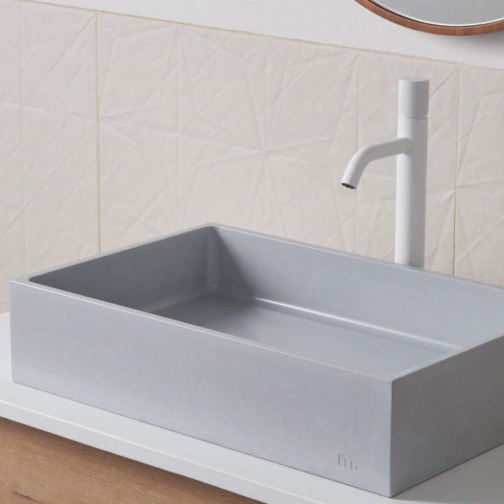 A mudd. concrete Jeker Basin sitting on top of a wooden counter.