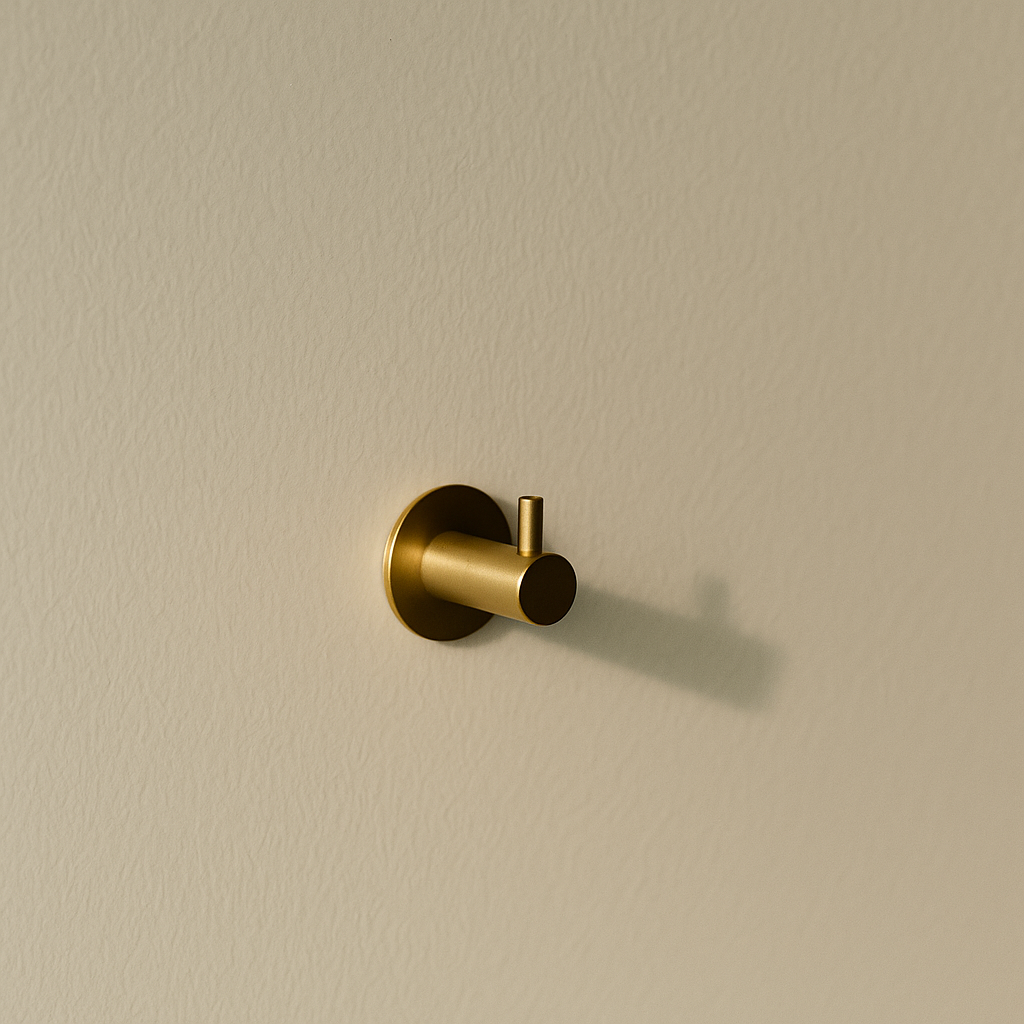 PVD satin brass d line Knud coat hook with a pin on a wall.