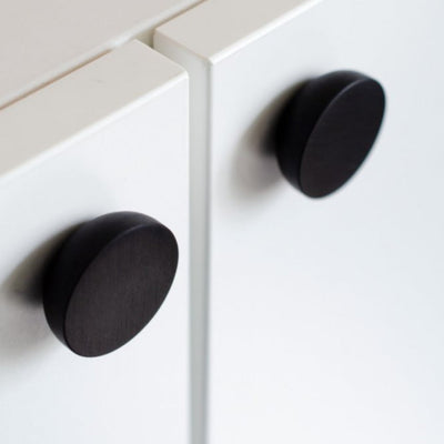 Round knob in black aluminum by Baccman Berglund mounted on white cabinet