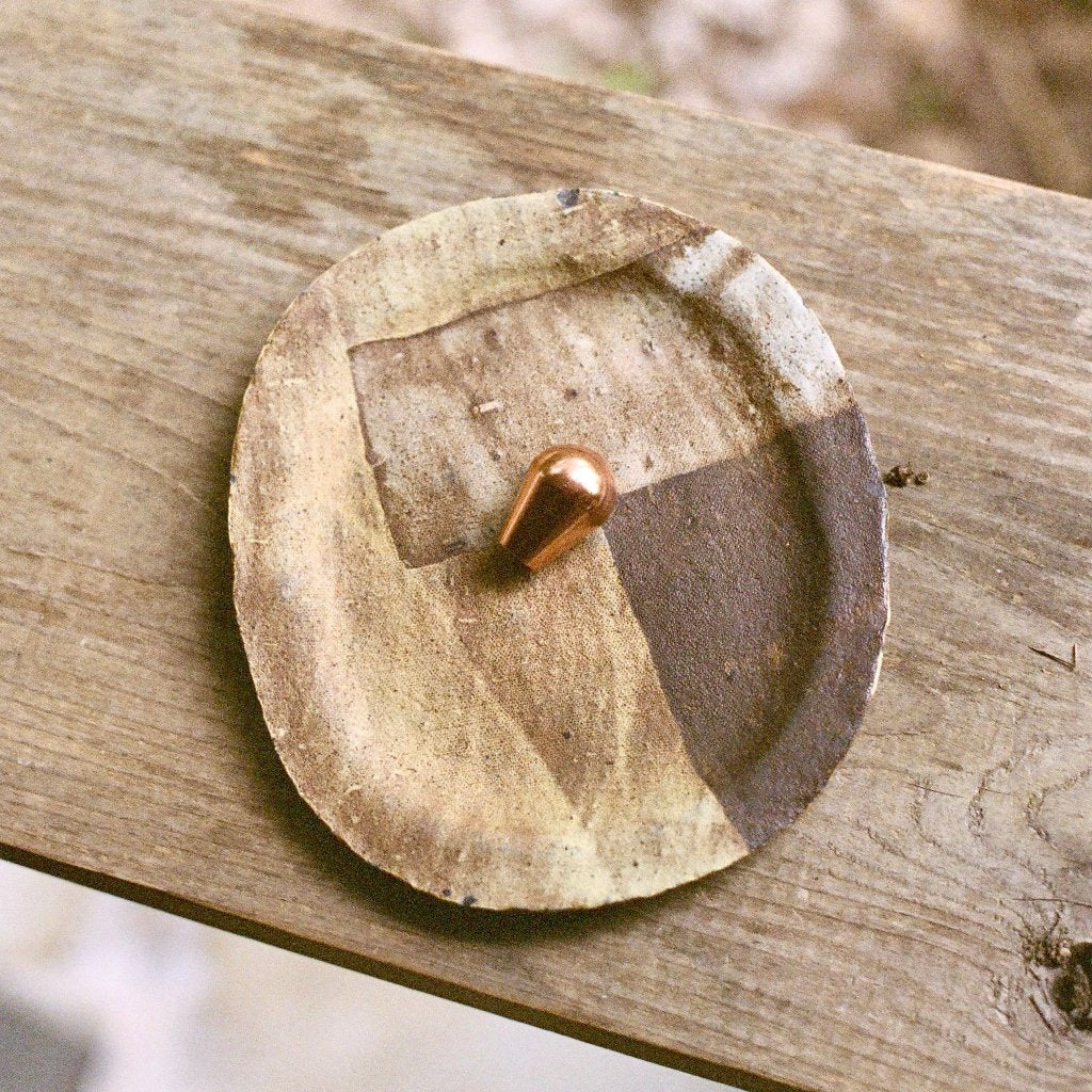 Cast bronze Maha Alavi LUA knob, a rounded ball, styled on a wood disc.