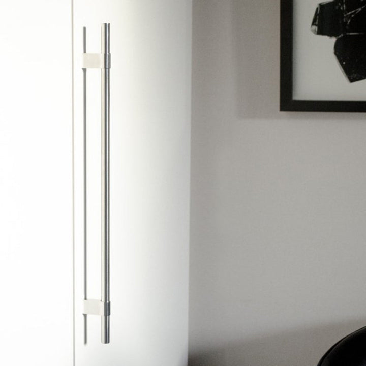 A white Baccman Berglund Line Big Handle refrigerator freezer sitting next to a black chair.
