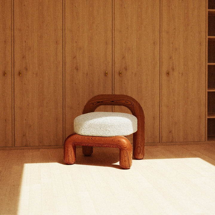 lithic lounge chair in red oak with beige upholstery seating in wooden room with large cabinets