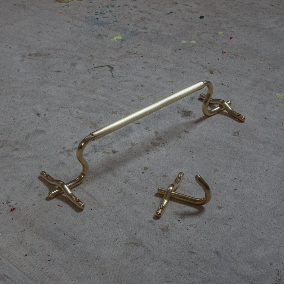 Brass ALL BETTER WORKSHOP Luma hand towel bar on a concrete surface.