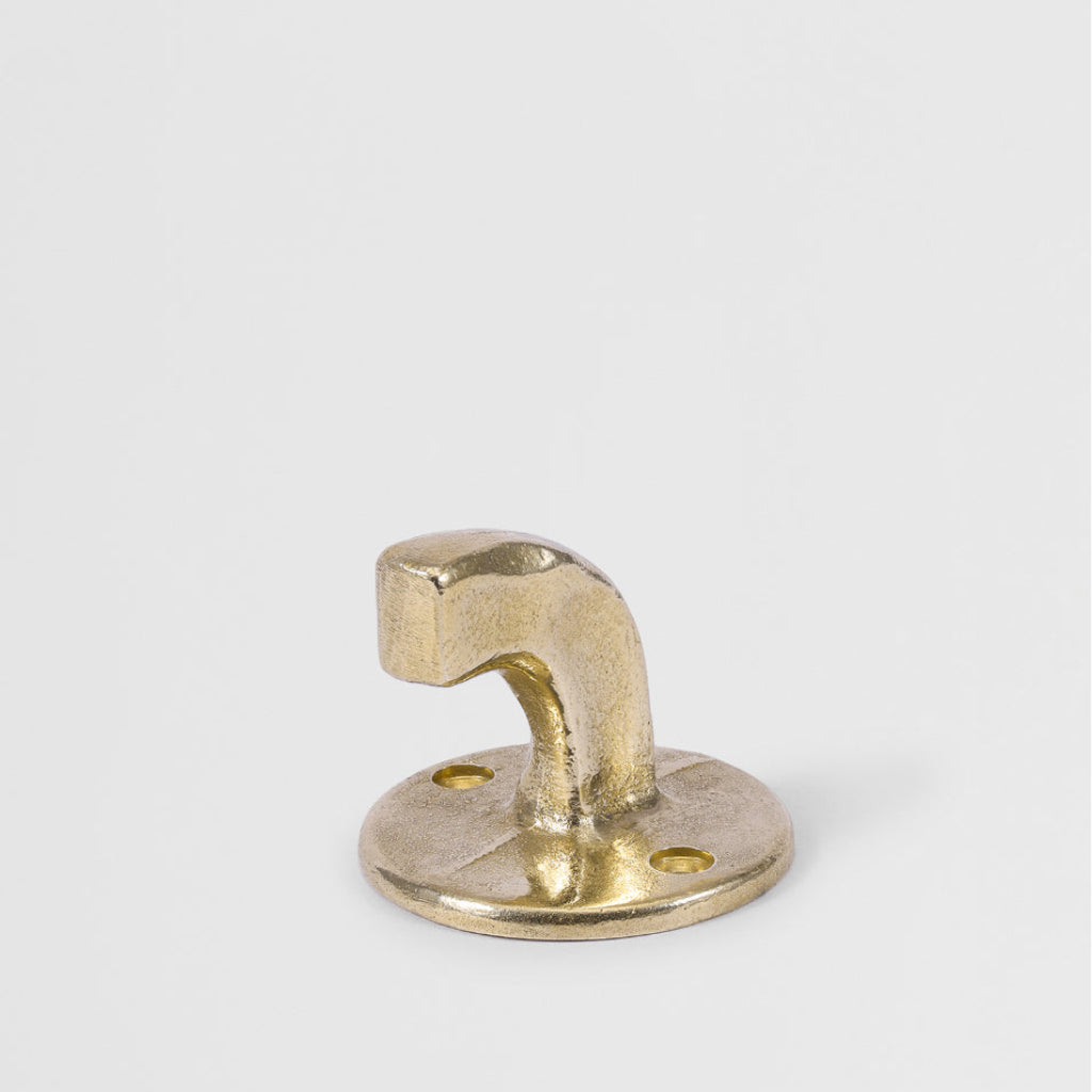Hand-cast solid brass Forme No. 8 hook with a curved, architectural profile and textured matte finish on a white background.