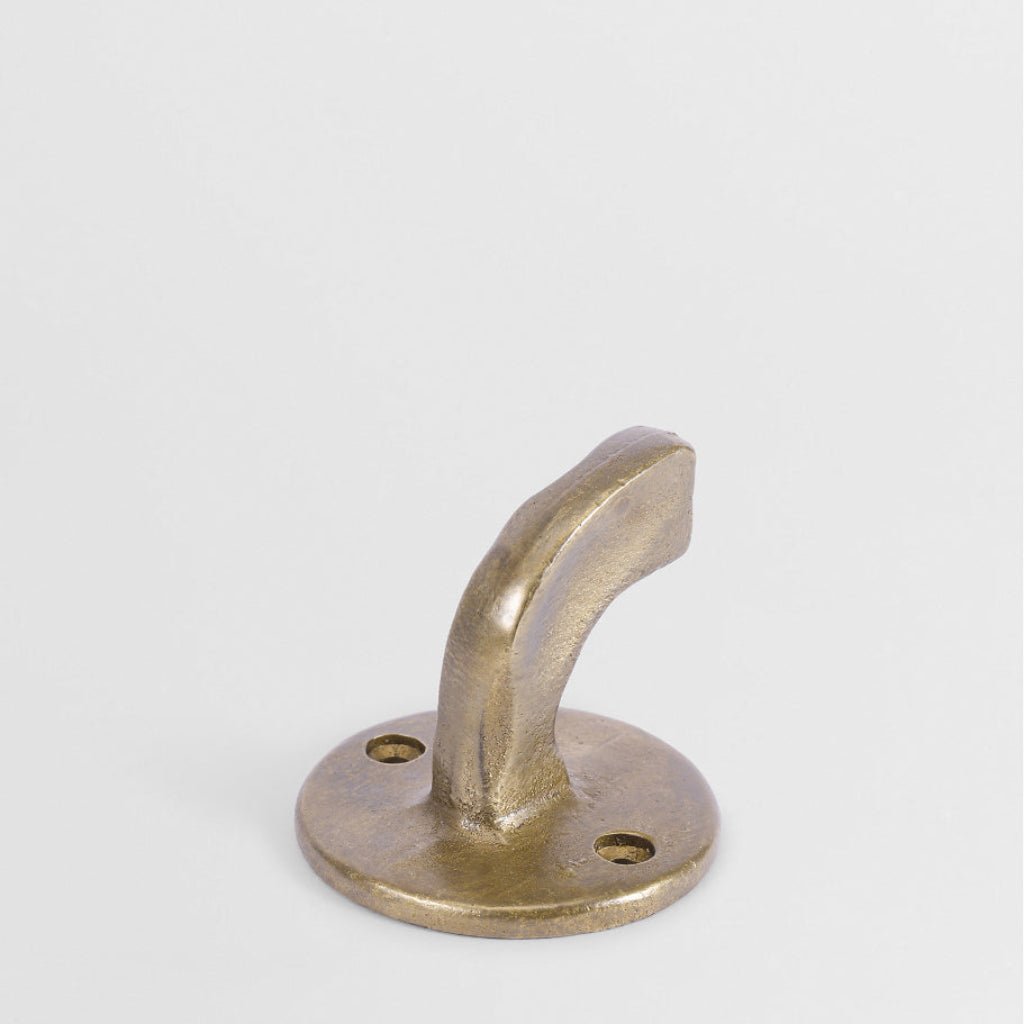 Hand-cast solid brass Forme No. 8 hook with a curved, sculptural profile and textured matte finish on a white background.