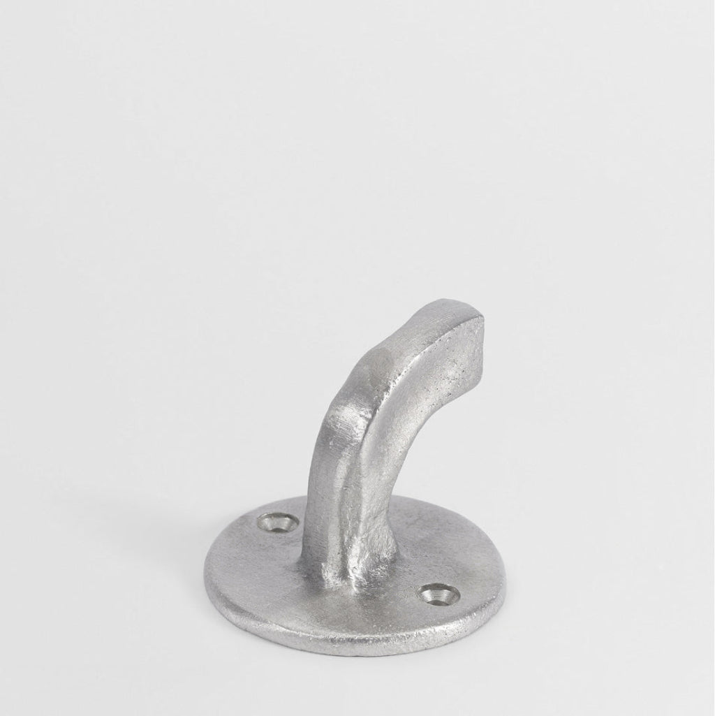 Hand-cast nickel finish Forme No. 8 hook with a curved, textured architectural design on a circular base.