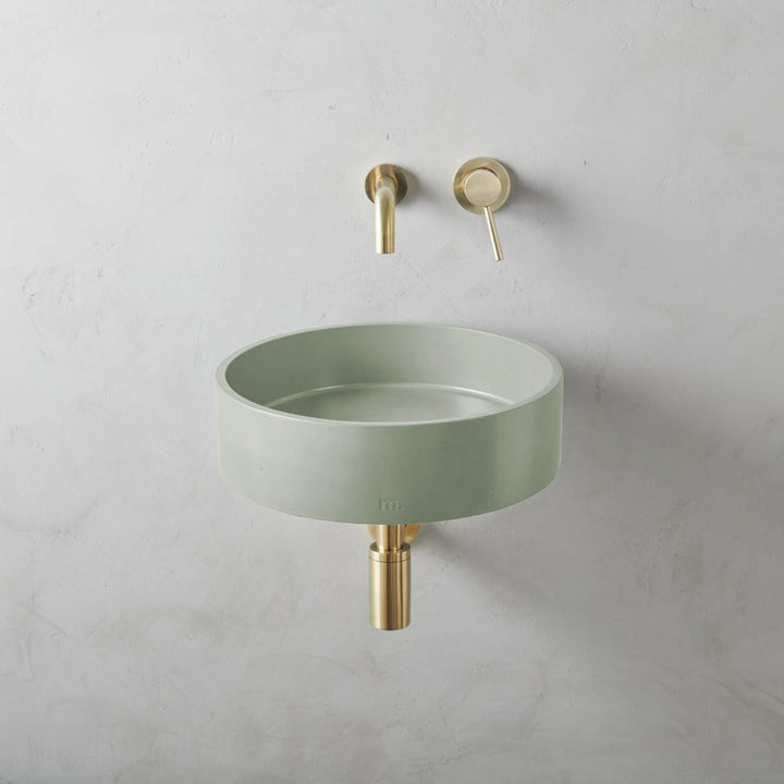 A Mudd. Concrete Odet Basin LG Affix with a gold faucet next to it.