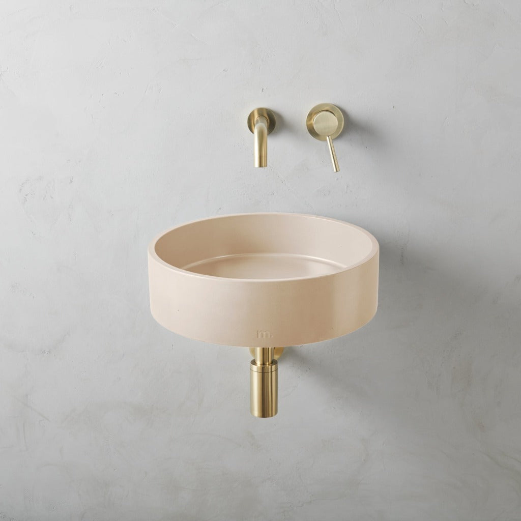 A mudd. concrete Odet Basin LG Affix with a gold faucet on the wall.