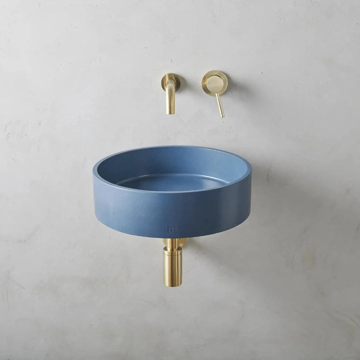 A Mudd. Concrete Odet Basin LG Affix with a gold faucet next to it.