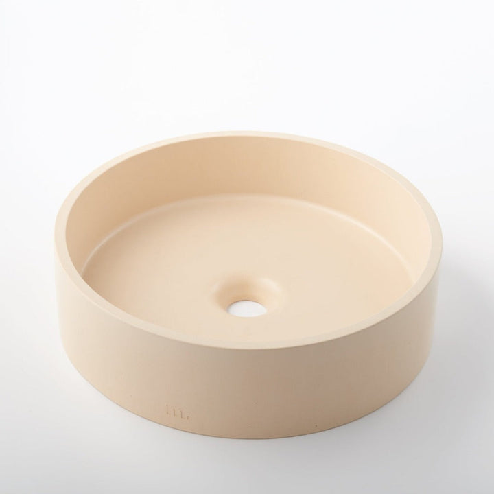 A round white Odet Basin LG sink by mudd. concrete on a white surface.